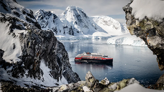 Cruise ship surrounded by water, glaciers and mountains.